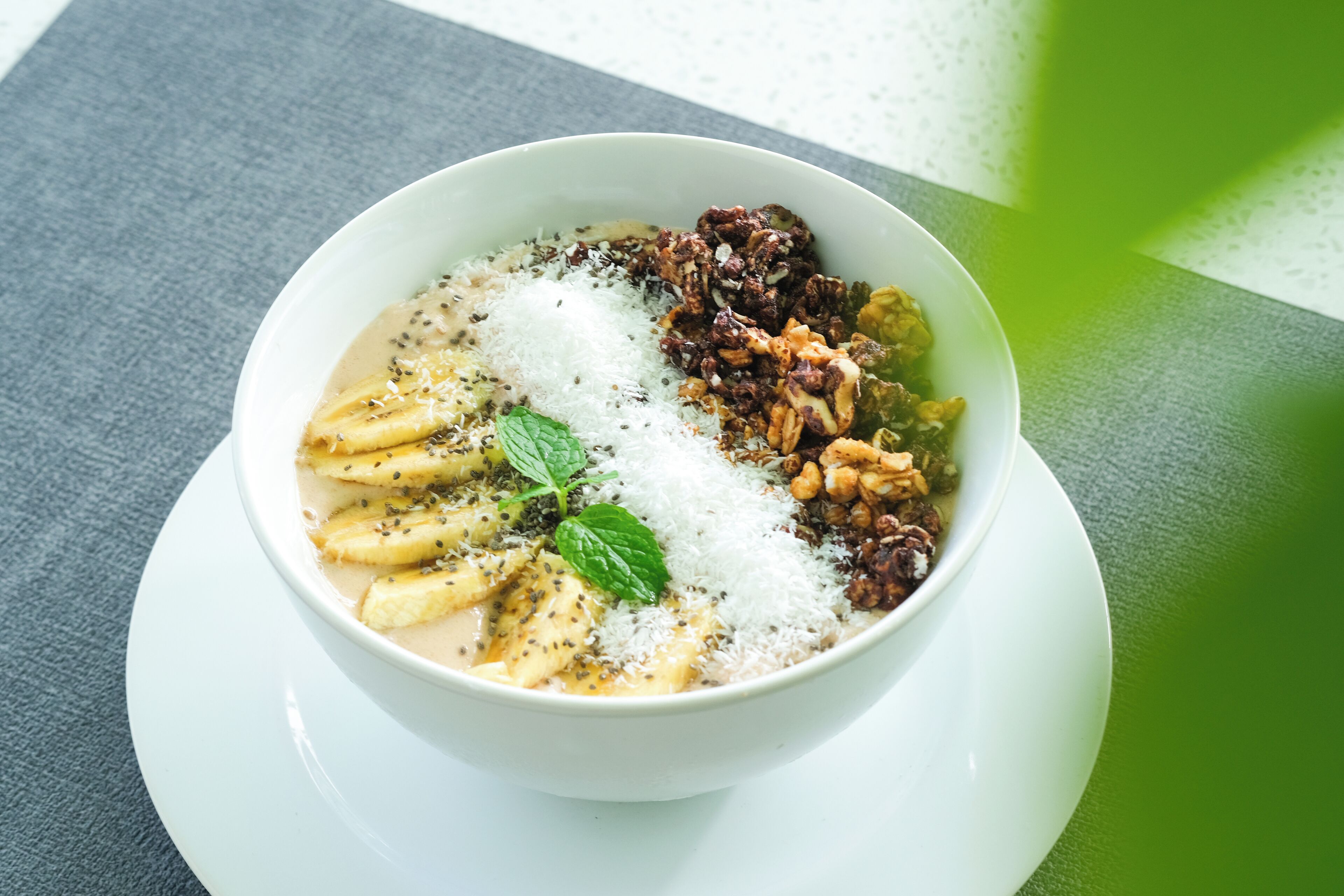 Un tazón de comida con distintos ingredientes, como nueces y semillas, sobre un plato blanco.