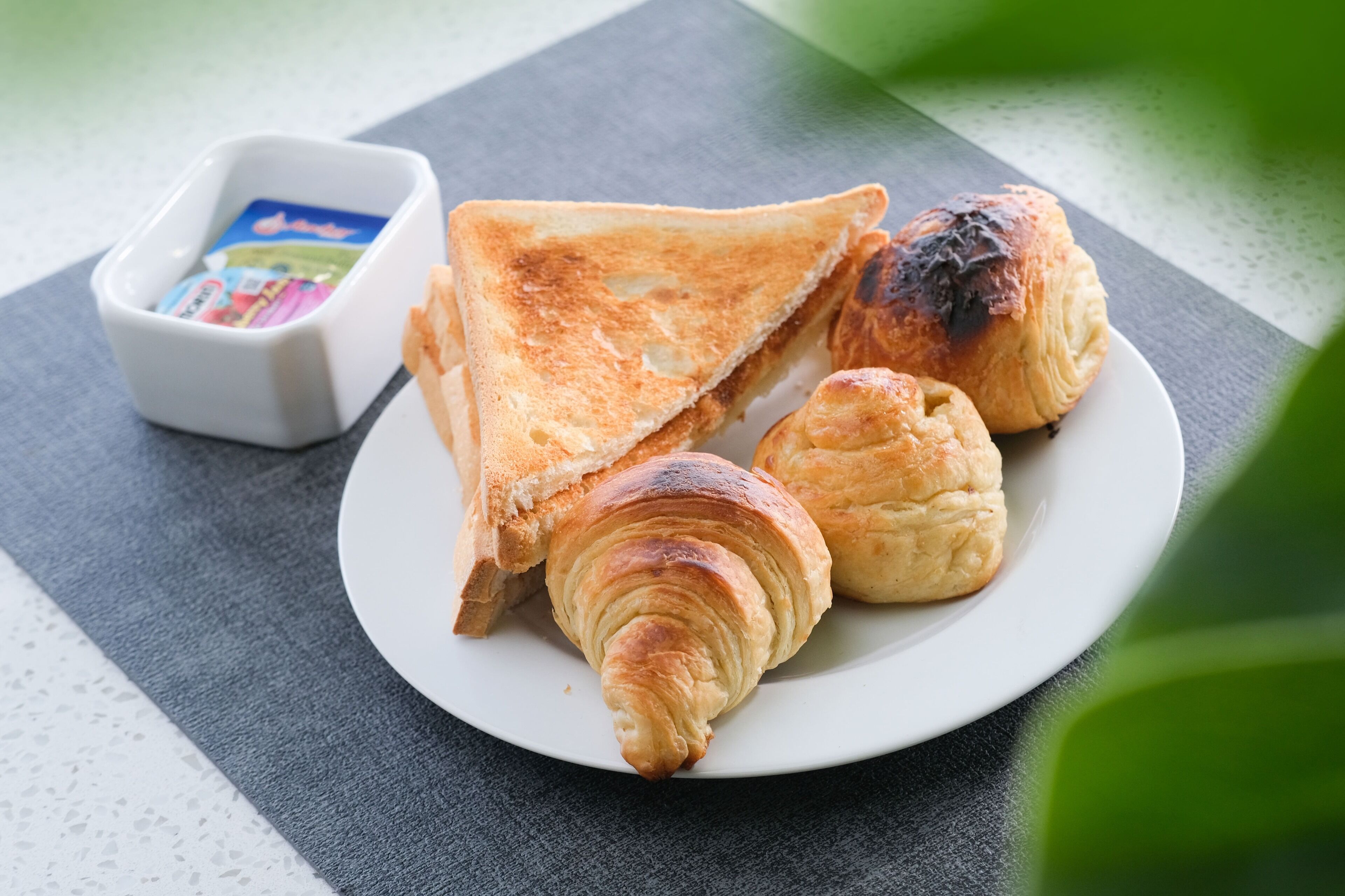 Une assiette contenant des tranches de pain grillé et des croissants, posée sur une table.
