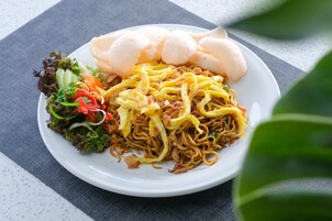 Un plato de fideos con verduras y una porción de pan.