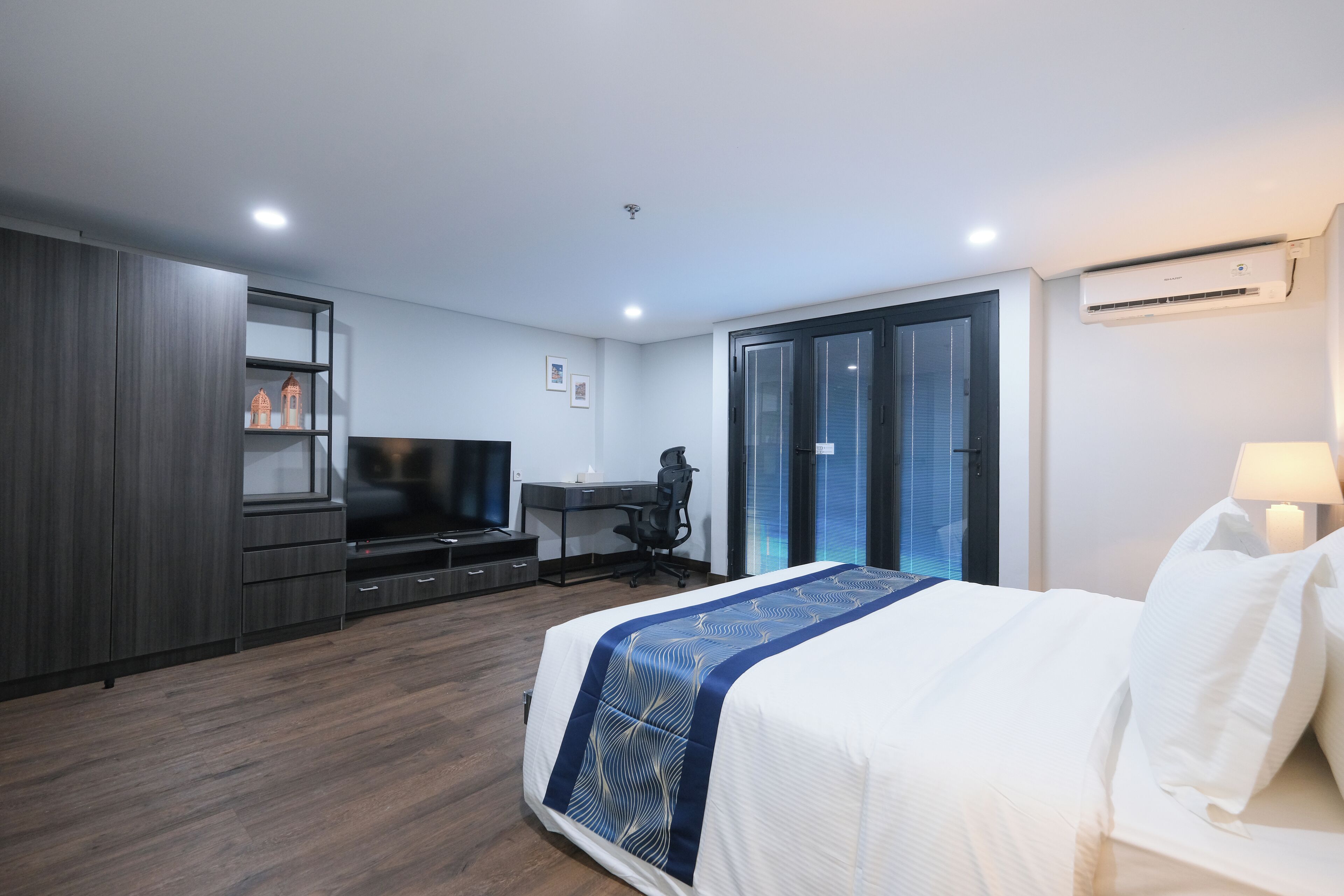 A modern hotel room with a large bed, a desk, and a wardrobe.
