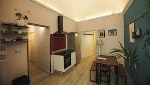 A compact kitchen with a modern stove, oven, and a built-in range hood. There is a dining area with a wooden table and chairs. - 4Brooms-Paladini b&b (Lecce)