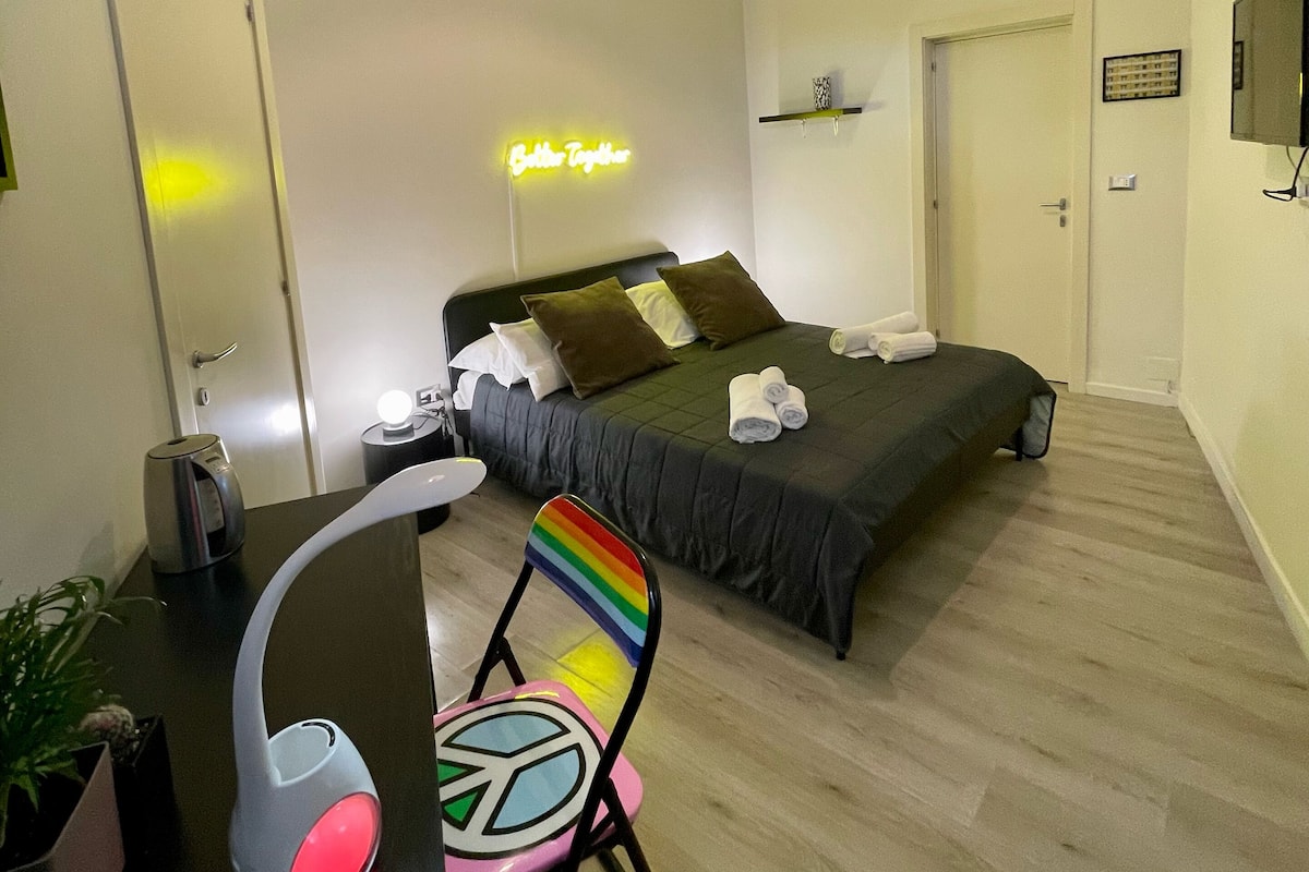 Une chambre à coucher moderne, avec un lit, une table de chevet, une chaise et un panneau lumineux néon.