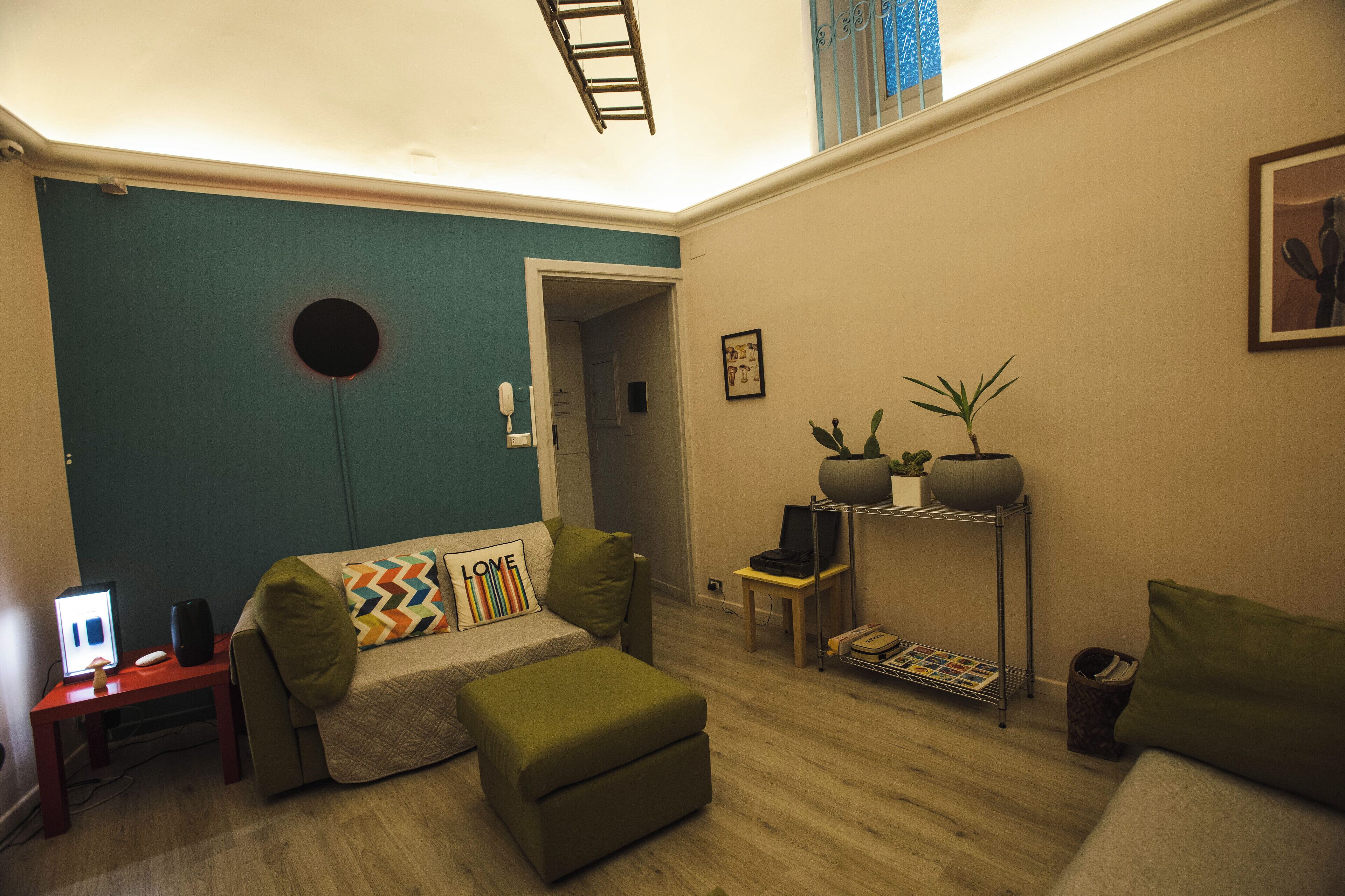 Una sala acogedora con un sofá, un reposapiés y una mesita de noche con una lámpara.