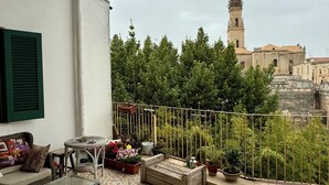 A balcony with a tiled floor, a wicker sofa, a glass table, and potted plants. - 4Brooms-Paladini b&b (Lecce)