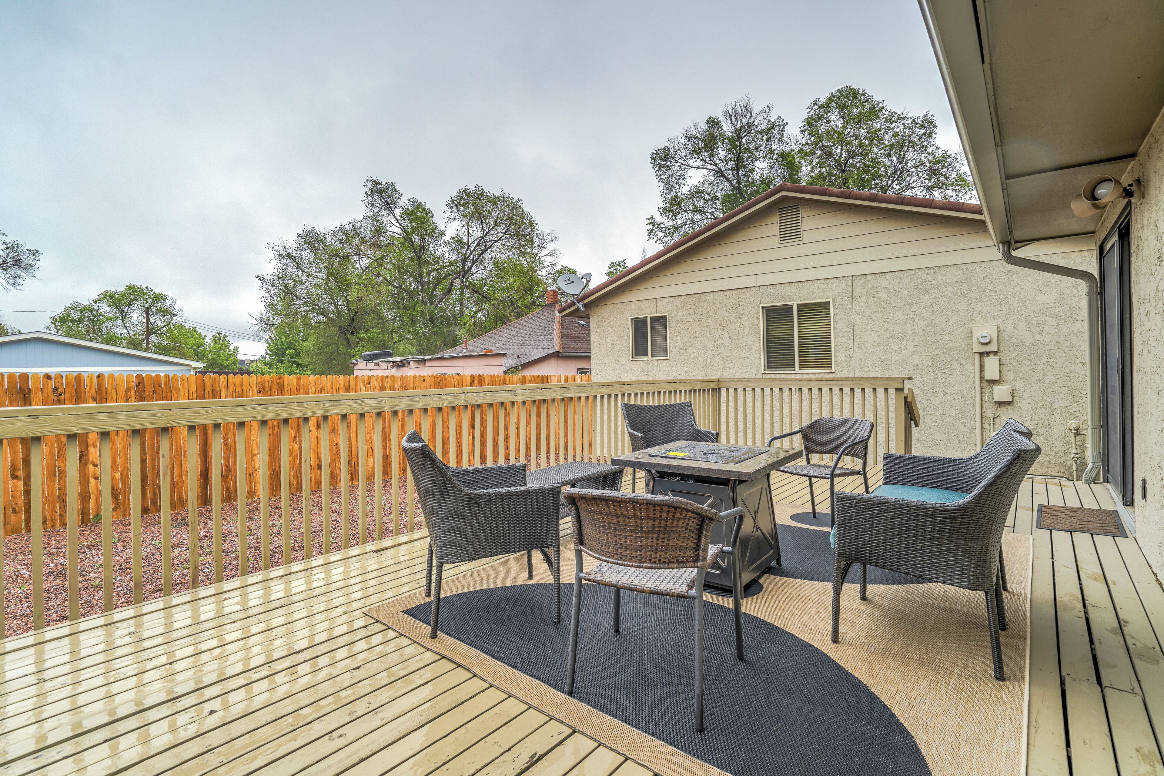 Una terraza de madera con mobiliario exterior, una mesa y sillas.