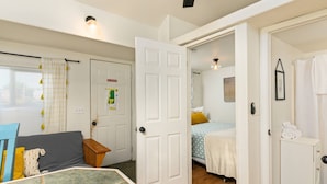 A cozy room with a bed, a small table, and a chair. There is a door leading to another room. - Outstanding Location, Pet Friendly, Kitchen, WiFi, Two Blocks From Beach, Unit 7 (Rockaway Beach)