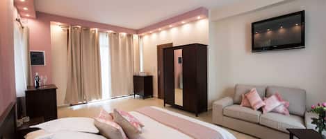 Een moderne slaapkamer met een groot bed, een bank, een televisie en een kledingkast.