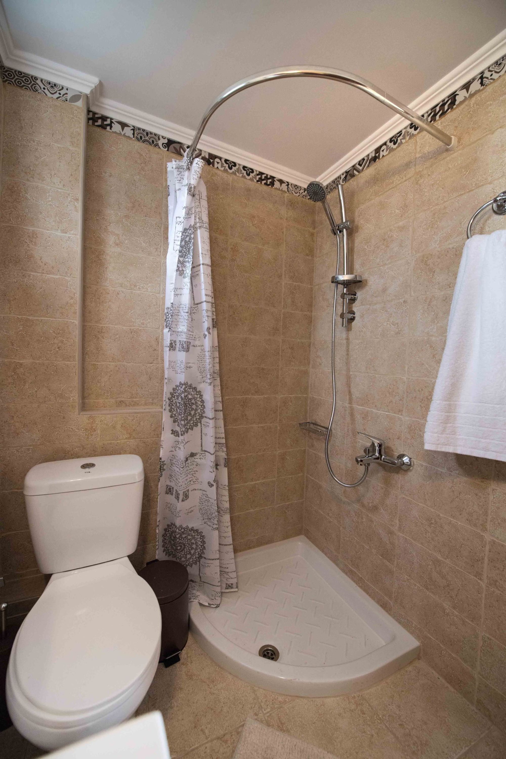 A bathroom with a shower, toilet, and a towel rack.