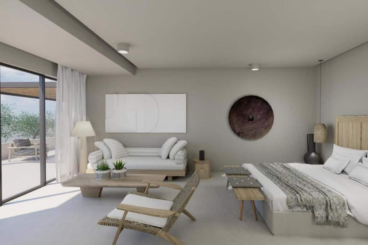 Une chambre moderne avec un grand lit, un canapé, un fauteuil et une petite table. Une grande fenêtre offre une vue sur l’extérieur.