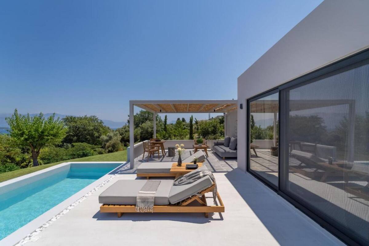 Un espace piscine extérieur moderne, doté de chaises longues et d’une pergola, offrant une vue sur un paysage luxuriant.