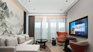 A modern living room with a sofa, a coffee table, and two chairs. A large TV is mounted on the wall. - Park Plaza Wenzhou (Wenzhou)
