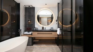 A modern bathroom with a freestanding bathtub, a vanity with a large mirror, and built-in shelves. - Park Plaza Wenzhou (Wenzhou)