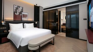 A modern hotel room with a large bed, bedside tables, a bench, a TV, and a sliding door leading to a bathroom. - Park Plaza Wenzhou (Wenzhou)