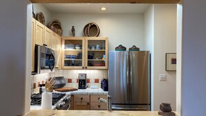 Una cocina con armarios de madera, un refrigerador de acero inoxidable, un microondas y una estufa a gas.