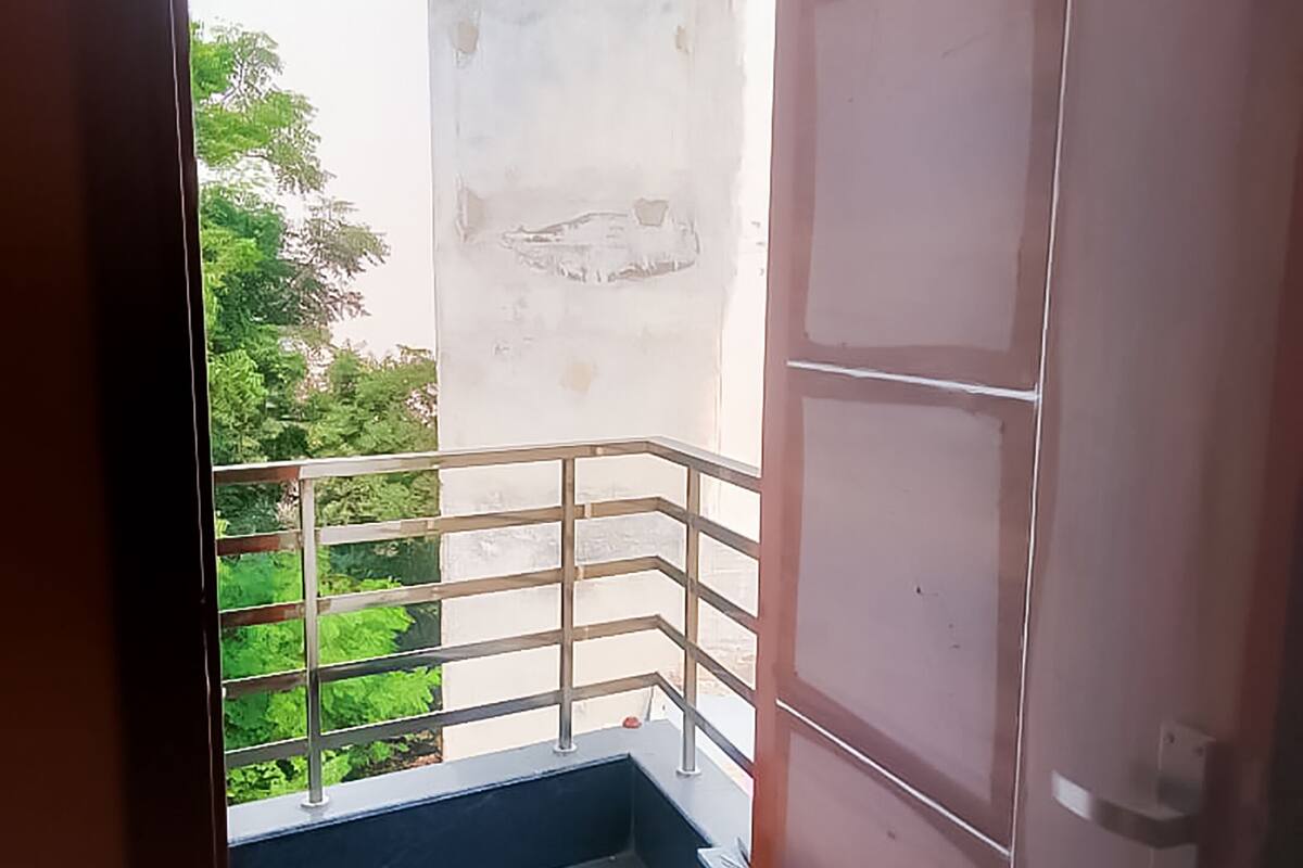 A narrow balcony with a metal railing, a concrete floor, and a view of greenery outside.