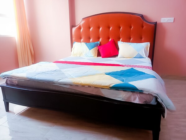 A bed with a tufted headboard, a quilt with a geometric pattern, and multiple pillows in various colors.