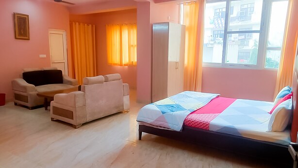 Un dormitorio con cama, dos sofás, un armario y una ventana con cortinas.