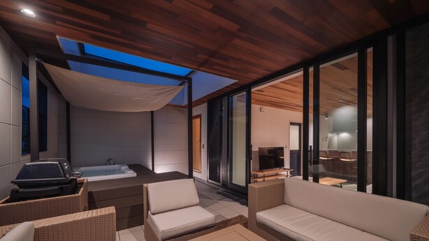 A modern outdoor living area with a sofa, chairs, a grill, and a bathtub. - VillaSanctuary＆SaunaOgimi (Ogimi)