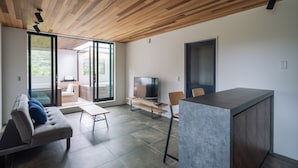 A modern living room with a wooden ceiling, a sofa, a TV, and a dining area. - VillaSanctuary＆SaunaOgimi (Ogimi)