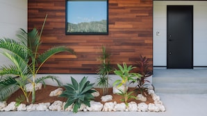 A modern building exterior with a wooden wall, a framed window, and a black door. - VillaSanctuary＆SaunaOgimi (Ogimi)
