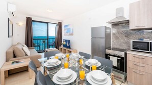 Une cuisine moderne avec un coin repas, un balcon offrant une vue agréable et un espace de vie comprenant un canapé et un téléviseur.