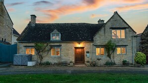 Une maison en pierre avec un toit sombre, une porte en bois et un petit porche.