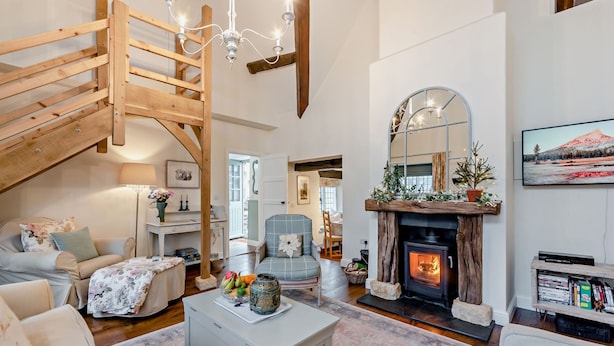 Un salon spacieux avec une cheminée, un escalier en bois et un coin salon confortable.