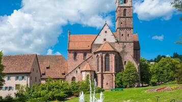 A historic church with a prominent clock tower, a fountain, and a well-maintained garden with benches.