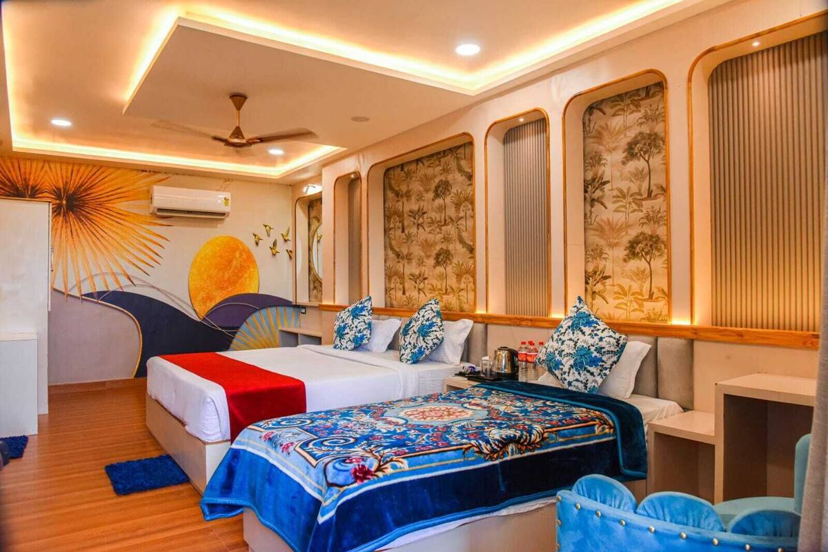 A hotel room with two beds, a ceiling fan, and a large window with a view of palm trees.