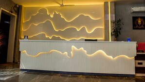 Un comptoir d’accueil doté d’un éclairage au design ondulant, un ventilateur de plafond et un climatiseur fixé au mur.