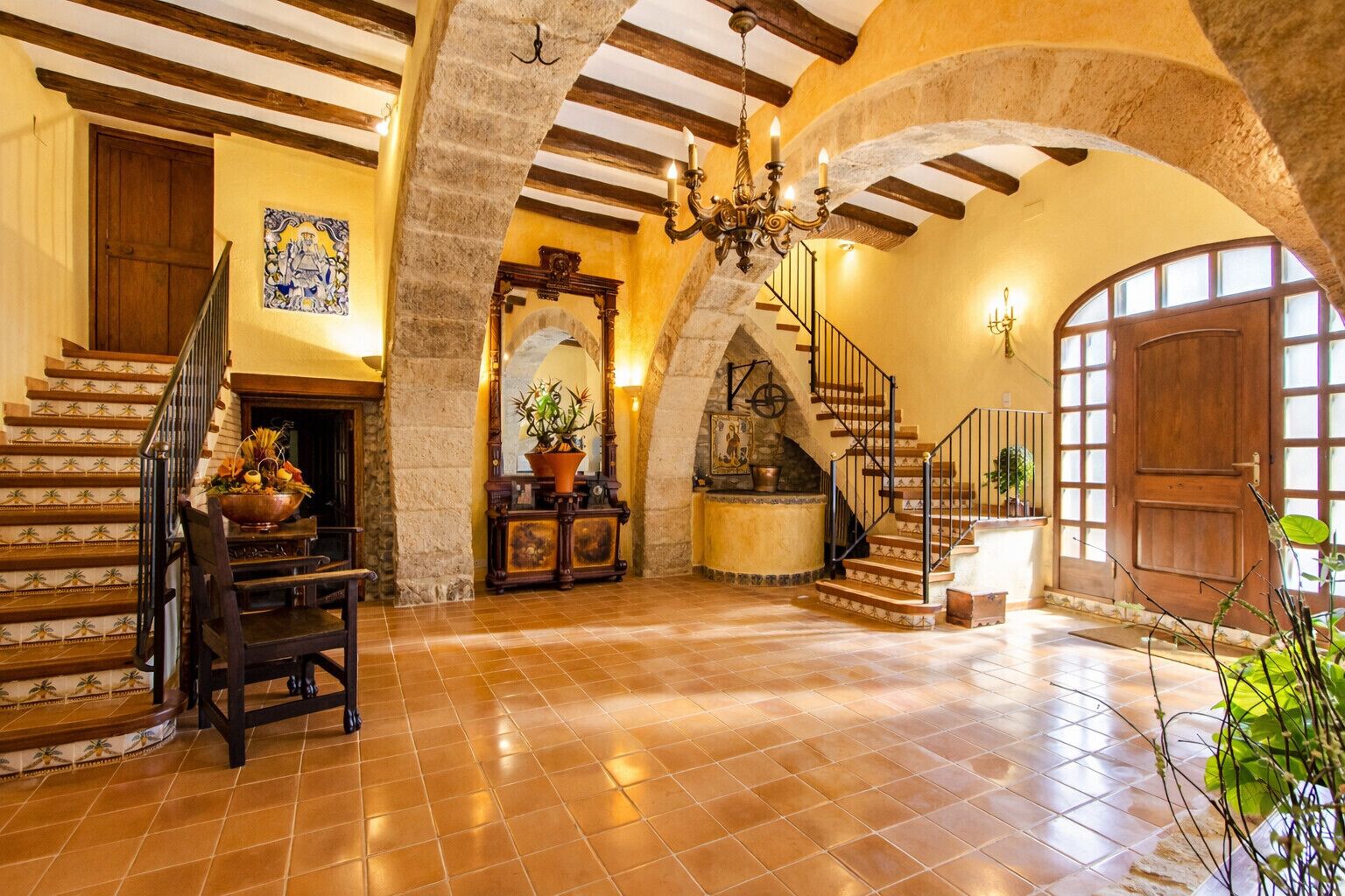 Un interior espacioso con una imponente escalera, una chimenea y un candelabro.