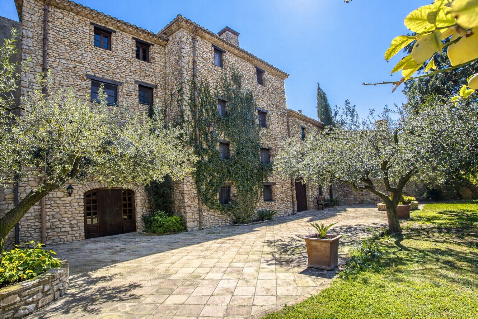 Un edificio de piedra con un patio, una puerta de madera y una planta en maceta.