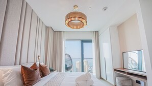 A modern hotel room with a large bed, a hanging chair, a television, and a view of the cityscape. - Modern 2BR HighFloor Haven - Vida Marina (Dubai)