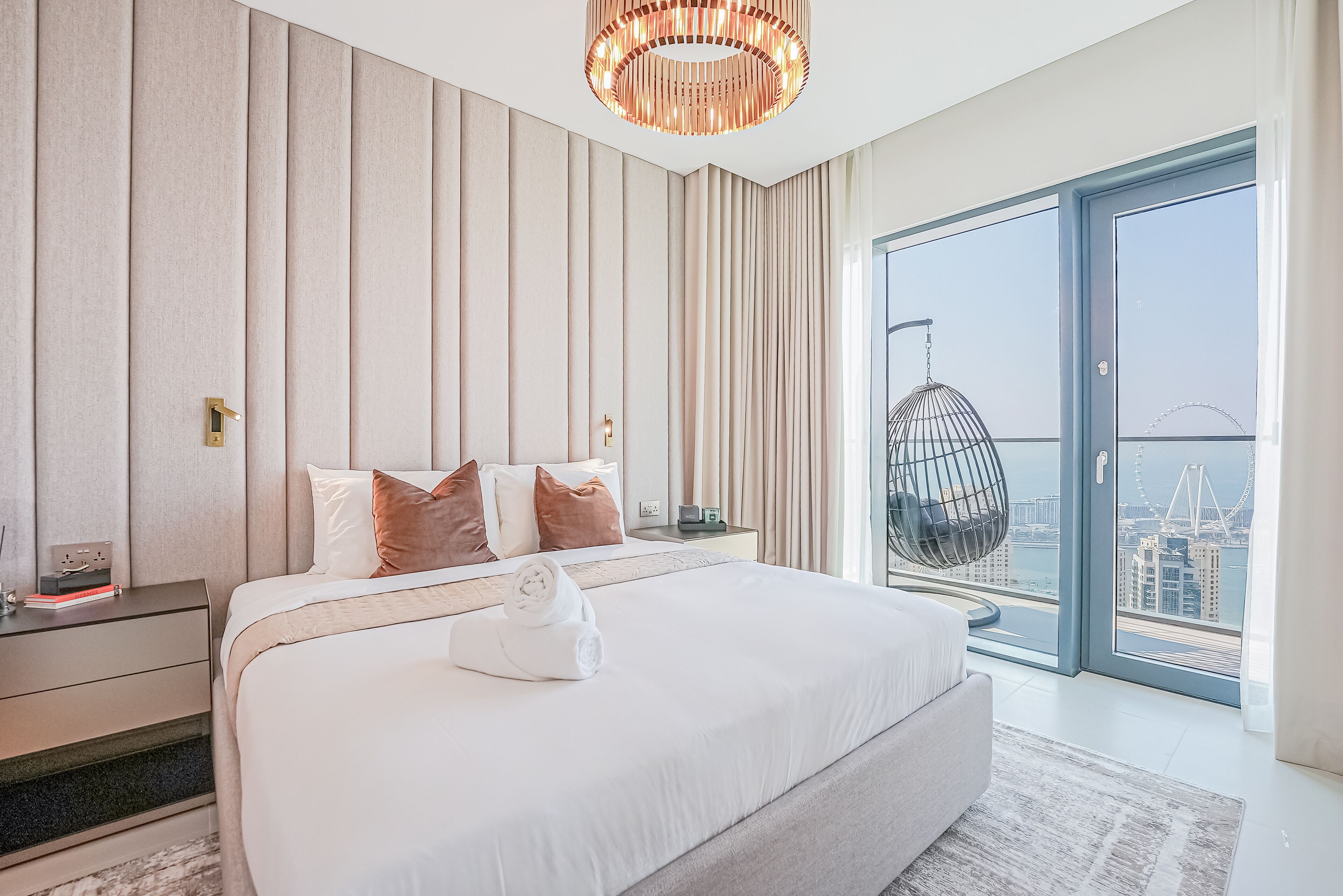 Une chambre d’hôtel moderne avec un grand lit, une vue sur une grande roue et un panorama sur la ville.