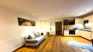 Un appartement moderne doté d’un salon avec un canapé et un plancher en bois.