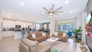 Ein modernes Wohnzimmer mit einer großen Couch, einem Couchtisch und einem Deckenventilator.