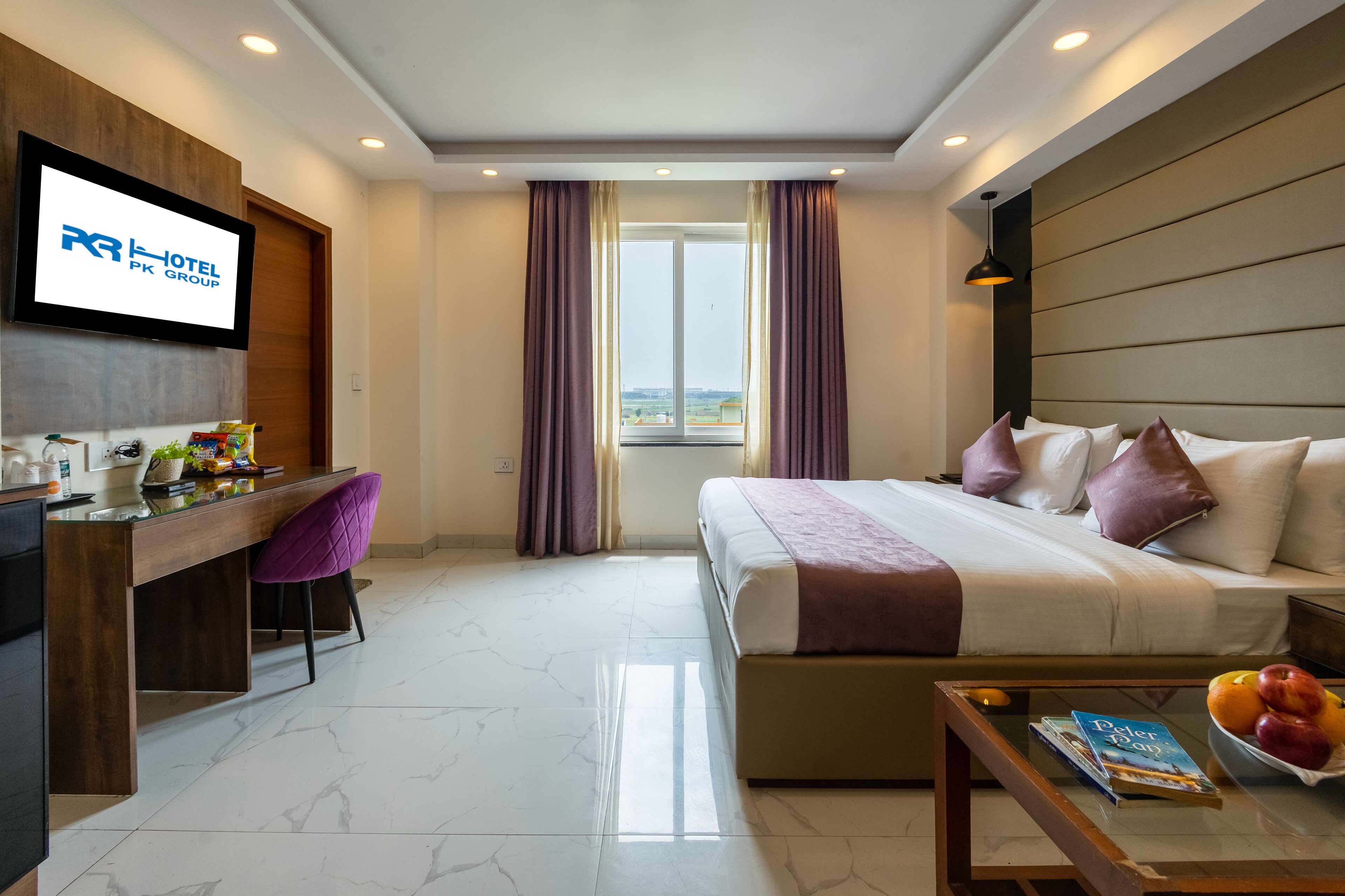A hotel room with a bed, desk, chair, and a TV displaying the hotel name.