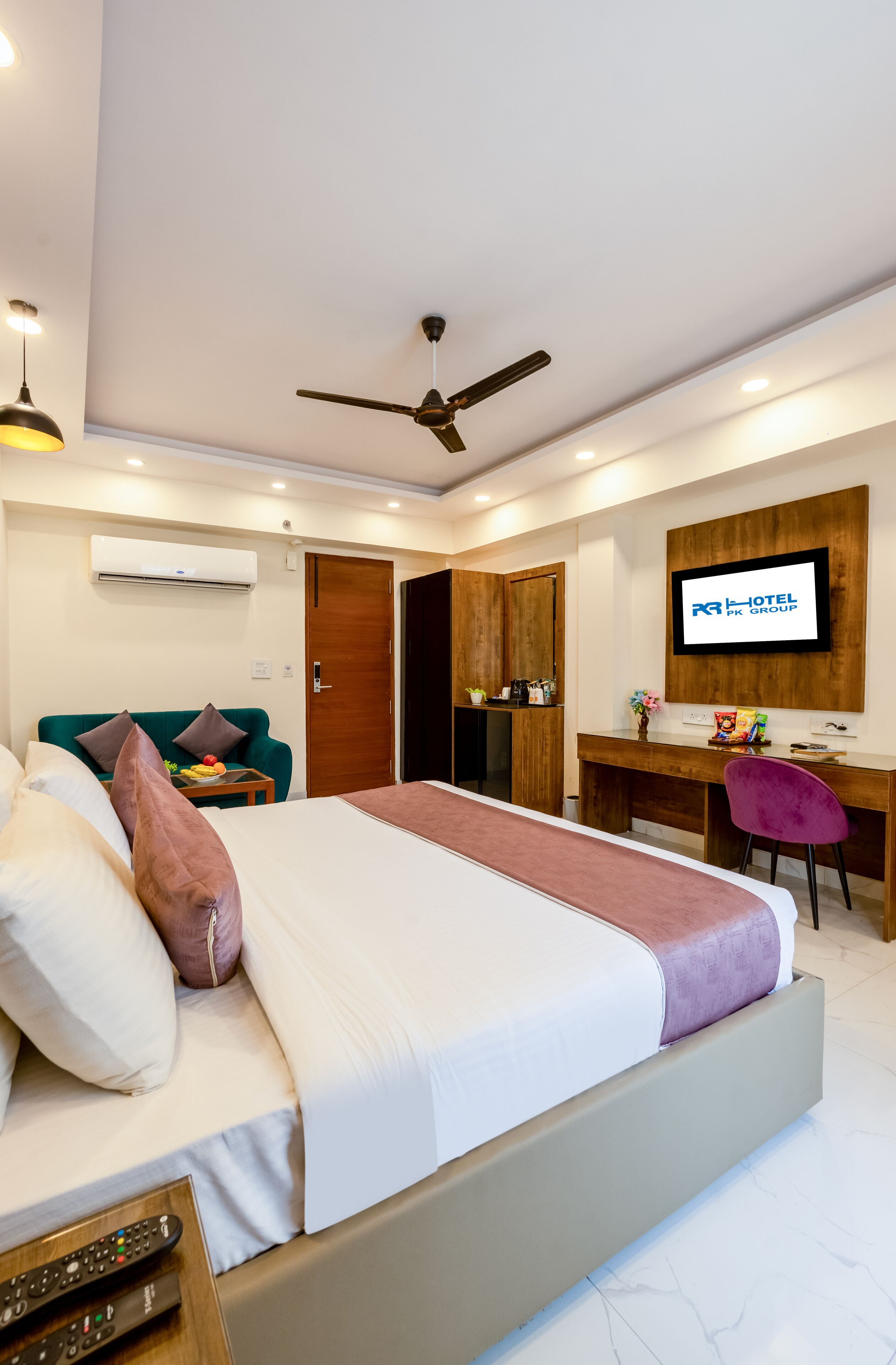 A hotel room with a bed, a desk, a TV, and a ceiling fan.