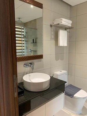 Et moderne badeværelse med et stort spejl, en hvid vask, et toilet og en håndklædestang.