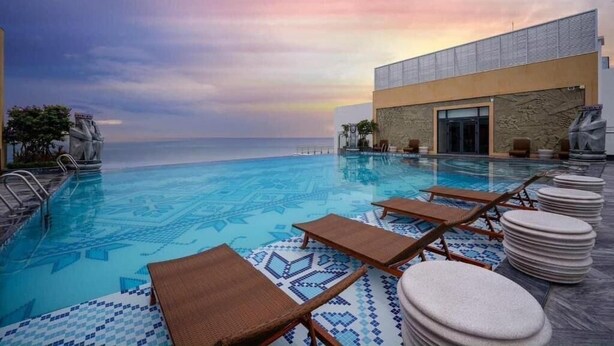 A poolside area with lounge chairs and a view of the sea. - Johnny Nguyen - Victor Condotel Phu Yen (Tuy Hoa)