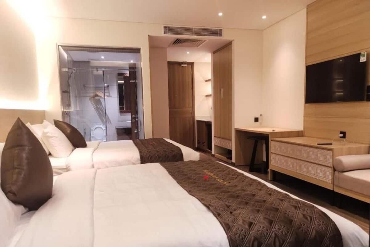Une chambre d’hôtel avec deux lits, un bureau, une télévision et un espace douche.