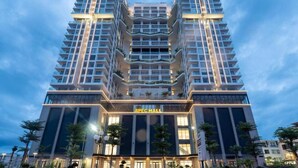 A modern APEC mall building with a symmetrical facade, multiple floors, and a central entrance. - Johnny Nguyen - Victor Condotel Phu Yen (Tuy Hoa)