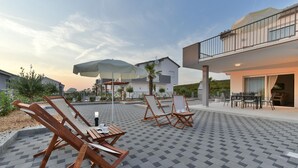 Eine Dachterrasse mit Holzliegen, einem Tisch und Sonnenschirmen.
