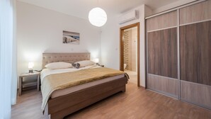 Ein Schlafzimmer mit einem großen Bett, Nachttischlampen, einer Hängeleuchte, einem Holzschrank und einem gerahmten Bild an der Wand.