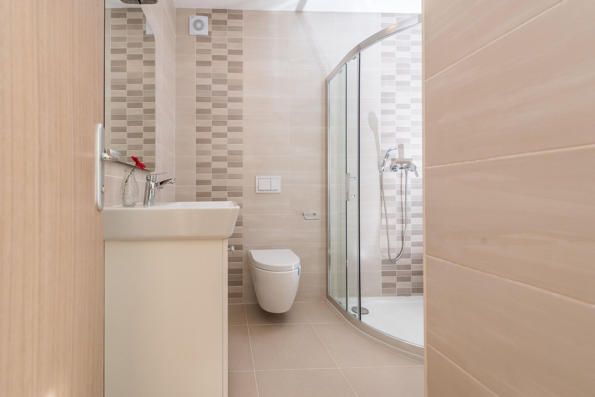 A modern bathroom with a glass shower enclosure, a toilet, and a sink with a mirror.