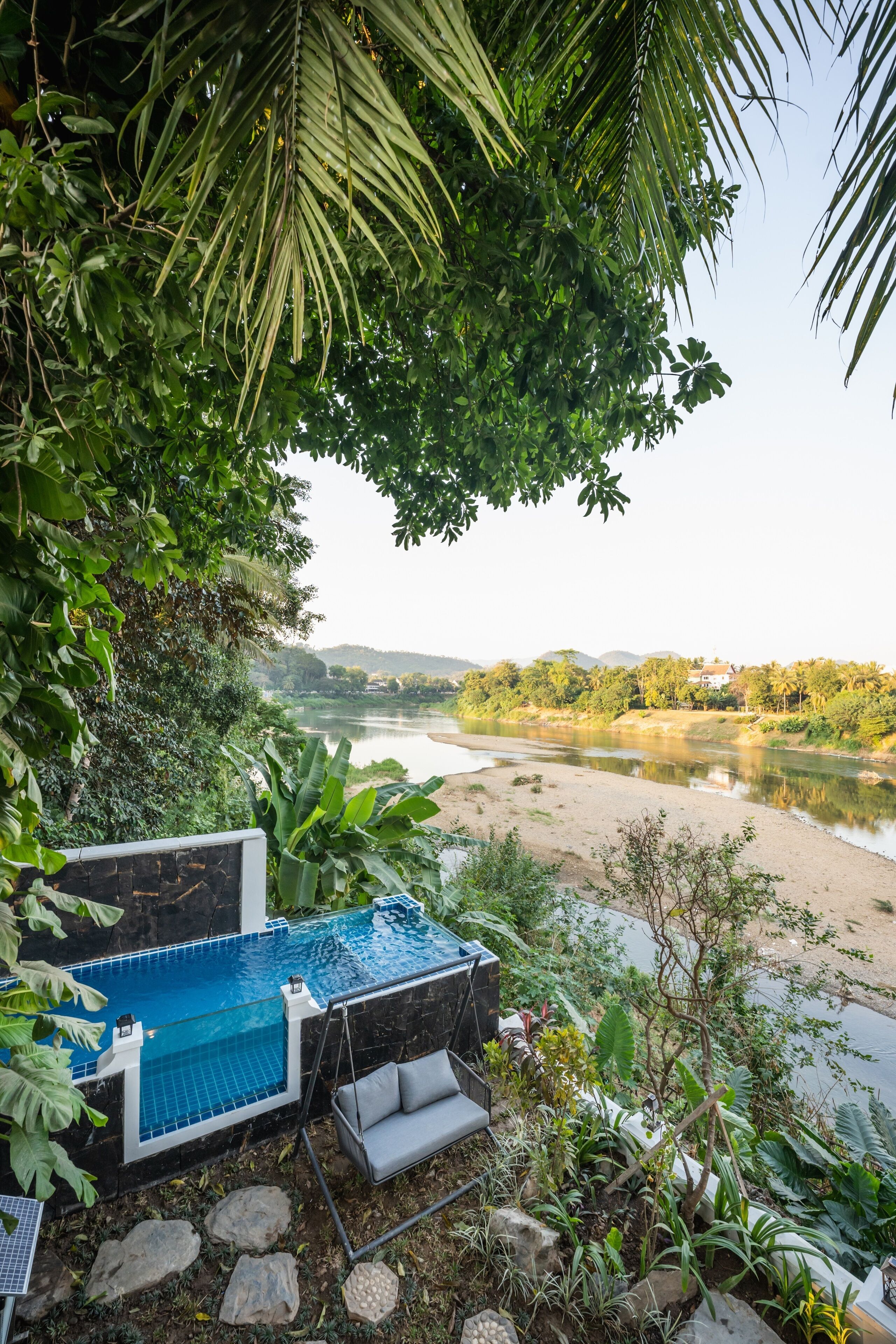A pool area with a view of a river and hills.