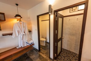 Ein Badezimmer mit Dusche, Toilette und einem Bademantel, der auf einem Wäscheständer hängt.