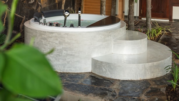 Un espace de bien-être aux murs de pierre, doté d’un jacuzzi et d’un plafond en bois.