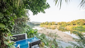 Une piscine avec un fauteuil suspendu et vue sur une rivière.