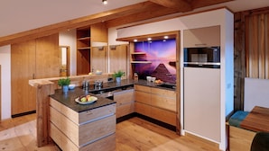 A modern kitchen with wooden cabinetry, a central island, and a built-in microwave. - Ferienwohnung Badesteg, 1-5pers., 2sep. SZ, Balkon mit Bergblick (Chieming)